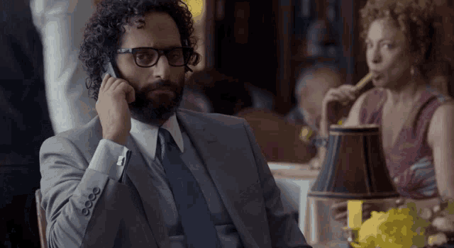 a man in a suit talks on a cell phone