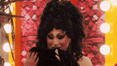 a woman in a black wig is holding a black cloth
