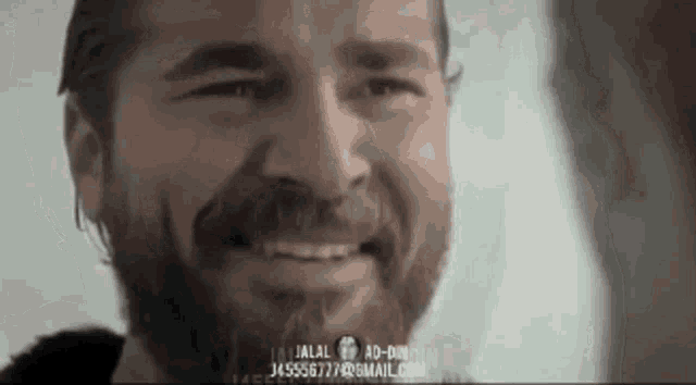 a man with a beard is smiling with a phone number on the bottom of his face