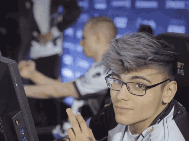 a man wearing glasses is sitting in front of a monitor that has the letter a on it