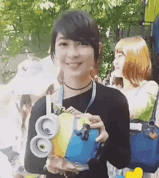 a woman in a black shirt is holding a blue and yellow object with the number 80 on it