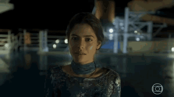 a woman in a blue dress is standing next to a swimming pool at night .