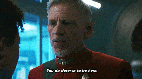 a man in a red uniform is talking to a woman and says you do deserve to be here