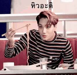 a man is eating noodles with chopsticks in a restaurant .