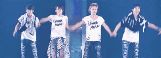 a group of men are standing on a stage holding hands and dancing .