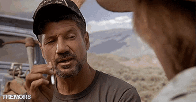 a man in a hat smoking a cigarette with the words themons on the bottom