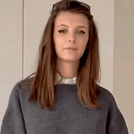 a woman wearing sunglasses and a blue sweater is making a face .