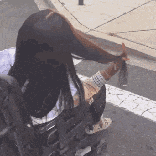 a woman in a wheelchair is holding her hair up