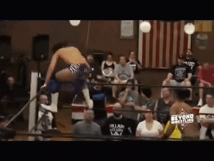 a wrestling match is taking place in a ring with a crowd watching .