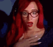 a woman with red hair is wearing glasses and a blue shirt