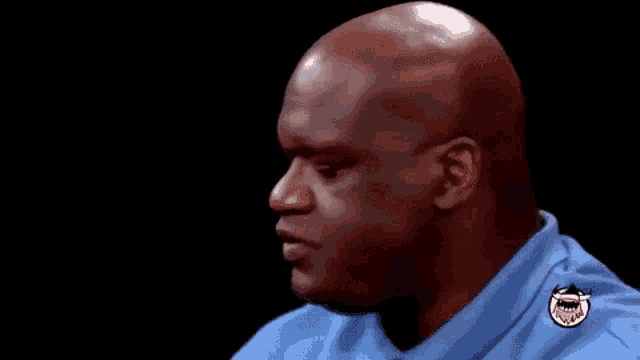 a bald man is wearing a blue shirt with a smiley face on the sleeve .