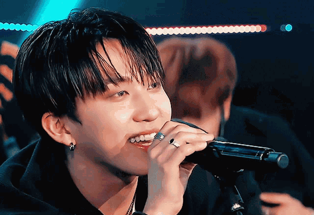 a young man singing into a microphone with his mouth open