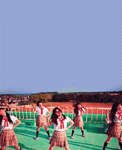 a group of girls in school uniforms are dancing on a green roof