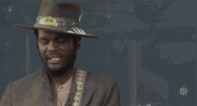 a man in a hat is playing a guitar in front of a sign that says hello