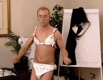 a man in a bra and panties is standing in front of a white board .