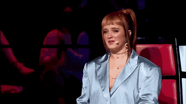 a woman with red hair is sitting in a chair with a microphone