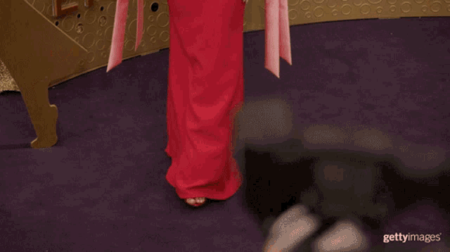 a woman in a red dress is standing in front of a wall with the word emm on it