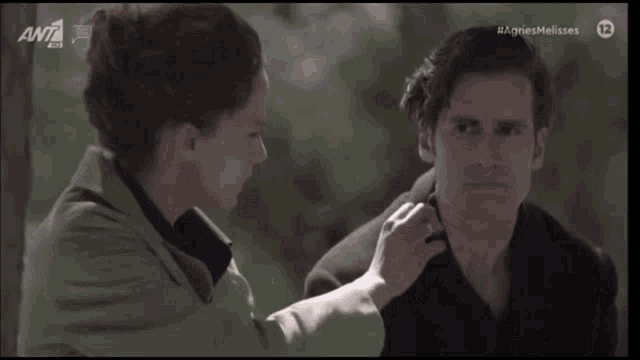 a woman is touching a man 's face with the letters ant on the bottom right