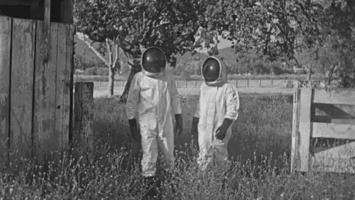 a black and white photo of two people wearing space suits