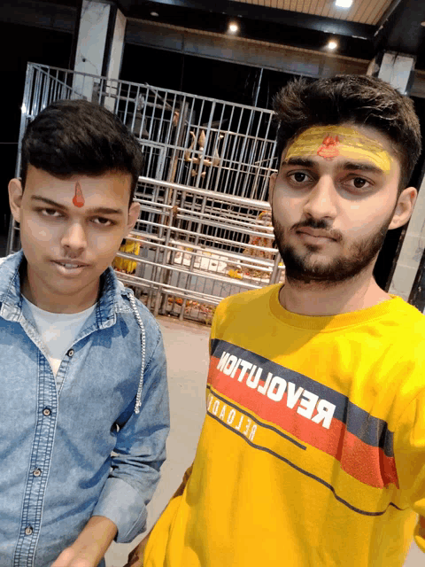 two men are posing for a picture and one of them is wearing a yellow shirt that says " motujove "