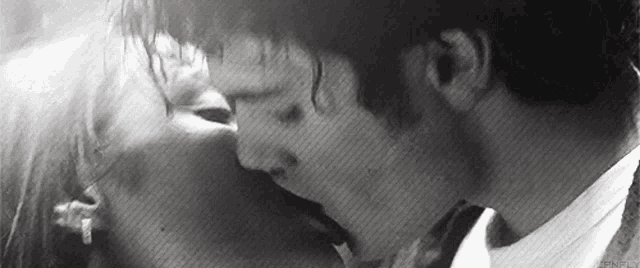 a man and a woman are kissing in the rain .