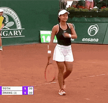 a woman is holding a tennis racquet on a court with a sign that says hungary in the background