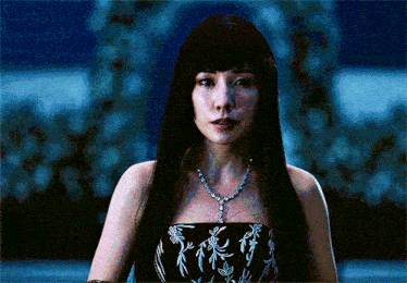 a woman with long black hair is wearing a necklace and a strapless dress