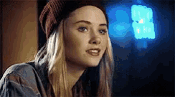 a close up of a woman wearing a beanie and a plaid shirt .