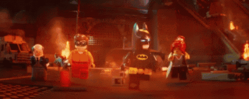 a group of lego figures are standing next to each other in a dark room .