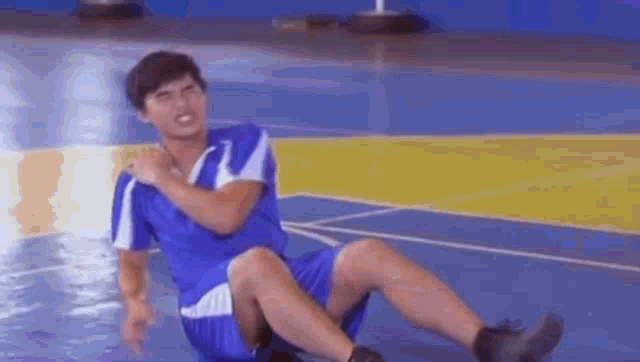 a man in a blue shirt and shorts is sitting on the floor .