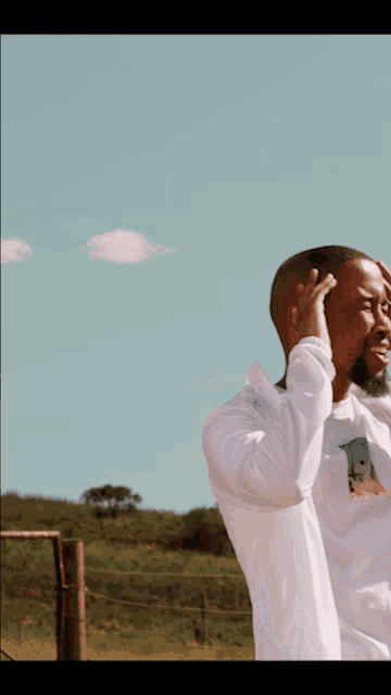 a man wearing a white shirt with the letter a on it stands in a field