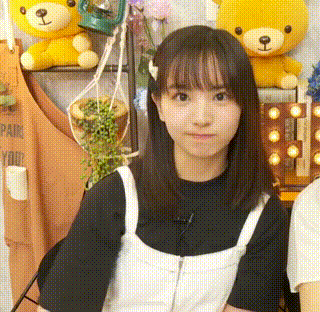 a young girl is sitting in a chair with her arms crossed and a teddy bear in the background .