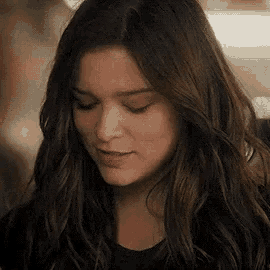 a close up of a woman with long dark hair looking down .