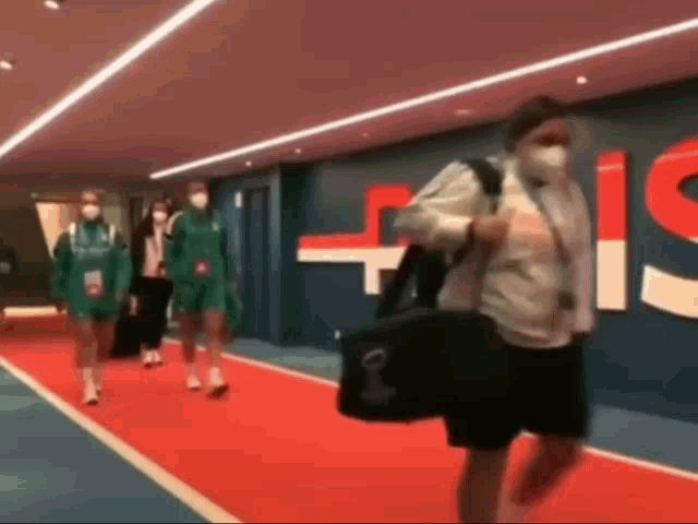 a group of people wearing face masks are walking down a red carpet .