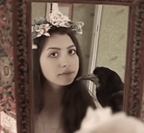 a woman with a flower crown on her head is looking at herself in a mirror