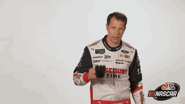 a man in a nascar uniform is holding a cup of coffee