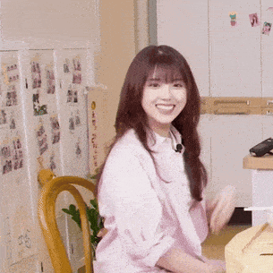 a woman in a pink shirt is sitting in a chair in front of a refrigerator