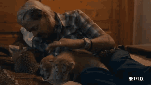 a man is laying on a bed playing with a cat and the netflix logo can be seen behind him