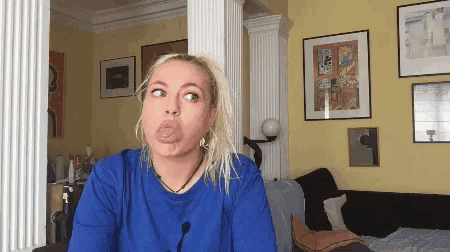 a woman in a blue shirt making a funny face in a living room