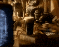 a glass of beer sits on a table in front of a tv screen