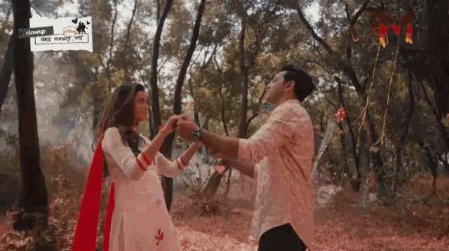 a man and a woman are dancing in the woods with a sign above them that says ' closing '
