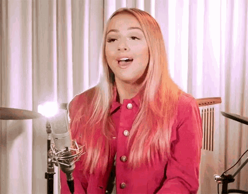 a woman in a red jacket is singing into a microphone .