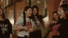 a group of young women are dancing in a room with their arms in the air .