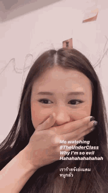 a woman covering her mouth with her hand while watching the under class