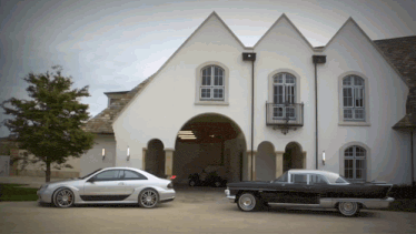 two cars parked in front of a large white house
