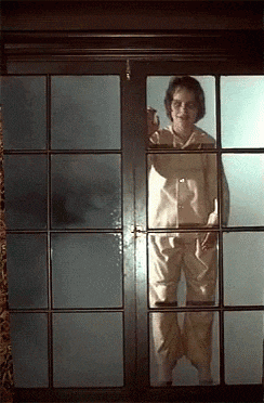a woman in pajamas is standing in front of a window