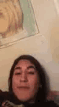 a woman is making a funny face in front of a painting of jesus on a wall .