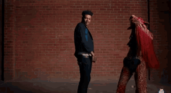 a man and a woman are posing in front of a brick wall