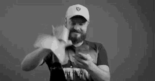 a man with a beard is holding a bunch of money in his hand and looking at his phone .