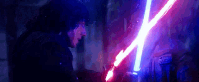 a man is holding a red and blue light saber in his hand .